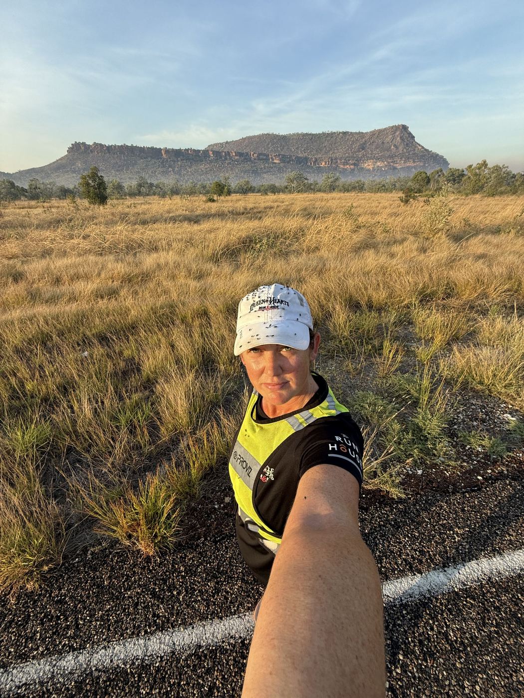 Dawn on a remote outback road with an escarpment behind her